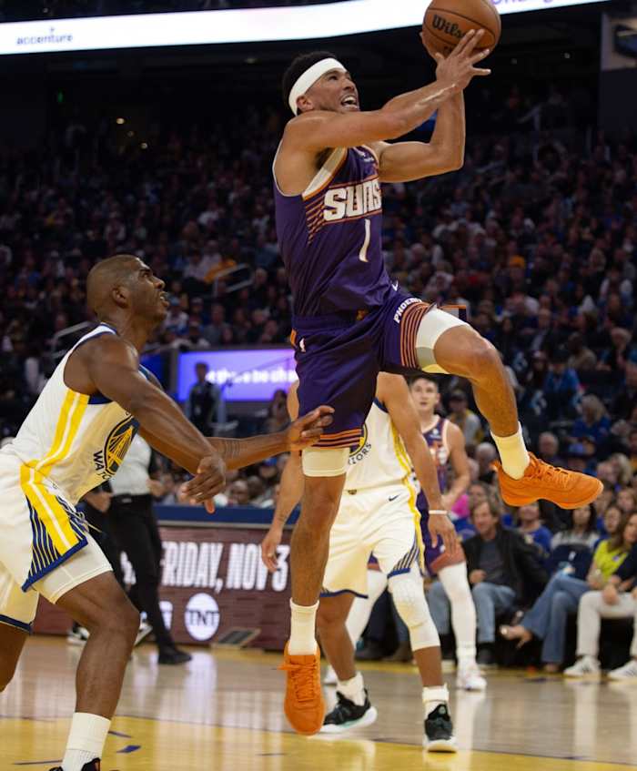 Phoenix Suns guard Devin Booker drives past Golden State Warriors guard Chris Paul
